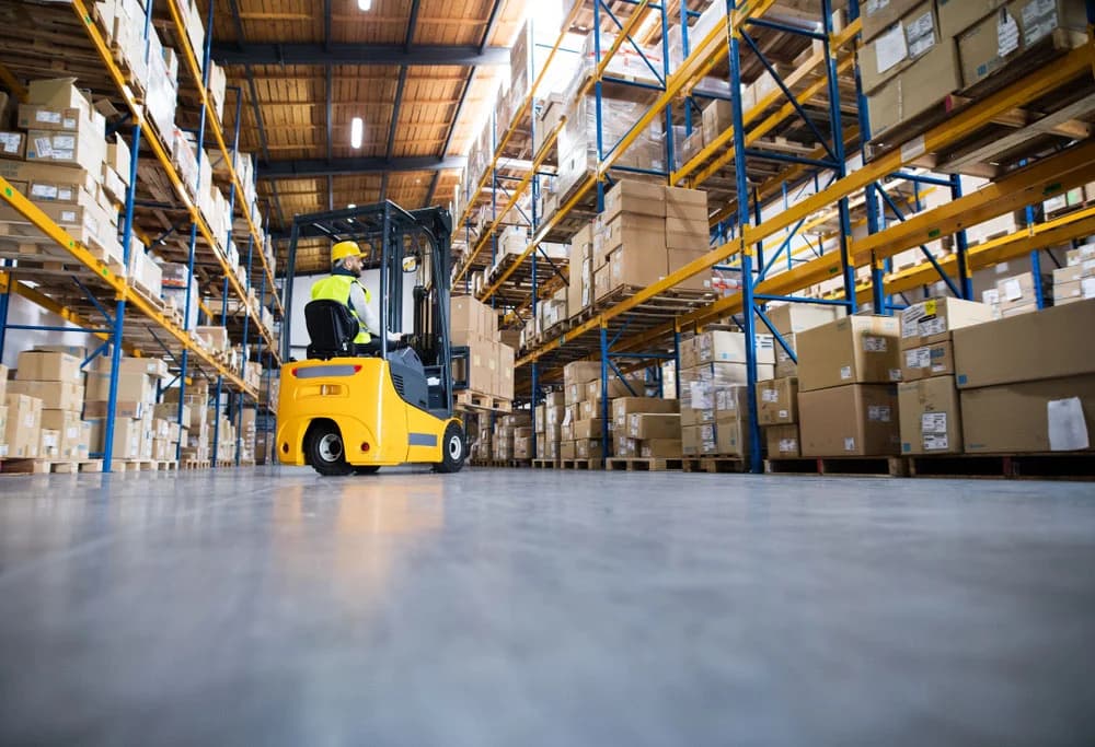 Forklift operator navigating warehouse aisles stacked with boxes in a 3PL facility