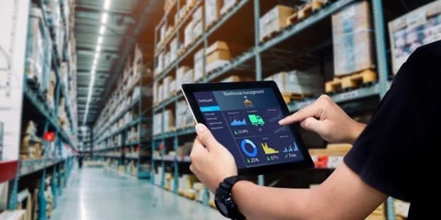 Warehouse worker using tablet with WMS SaaS dashboard for inventory management