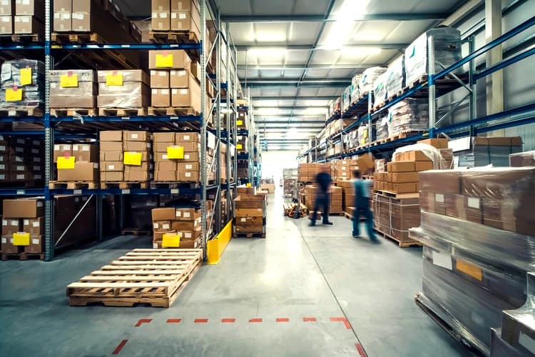 a warehouse full of boxes and two warehouse workers blurred showing movement