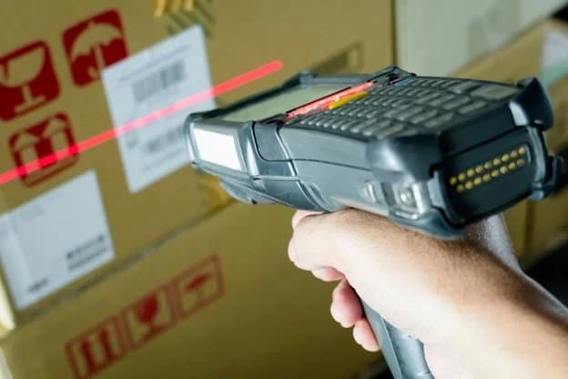 Warehouse operator scanning barcode on cardboard box with handheld laser scanner