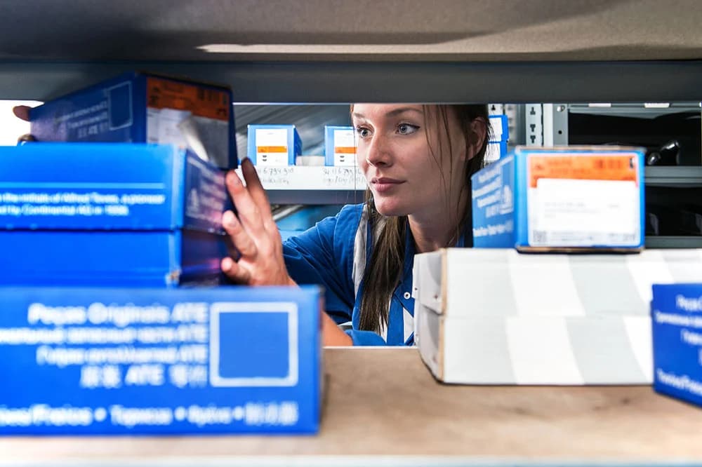 Warehouse worker organizing inventory boxes on shelves during pick and pack operations