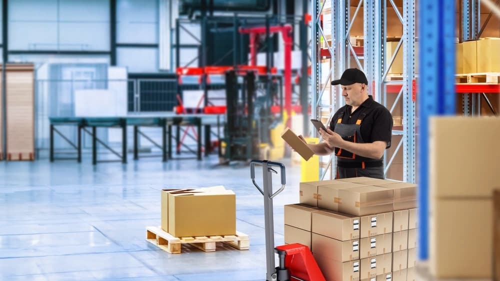 warehouse worker receiving inventory being a pallet of boxes into stock