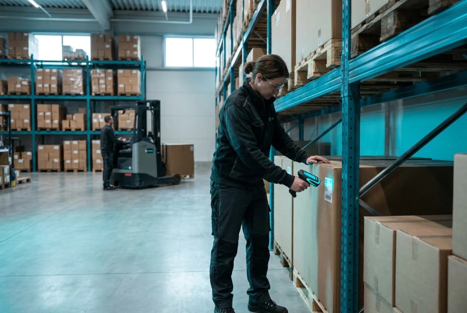Warehouse operator scanning barcode on cardboard box with handheld laser scanner