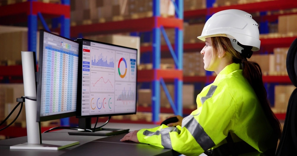 warehouse worker looking at charts and graphs on monitors