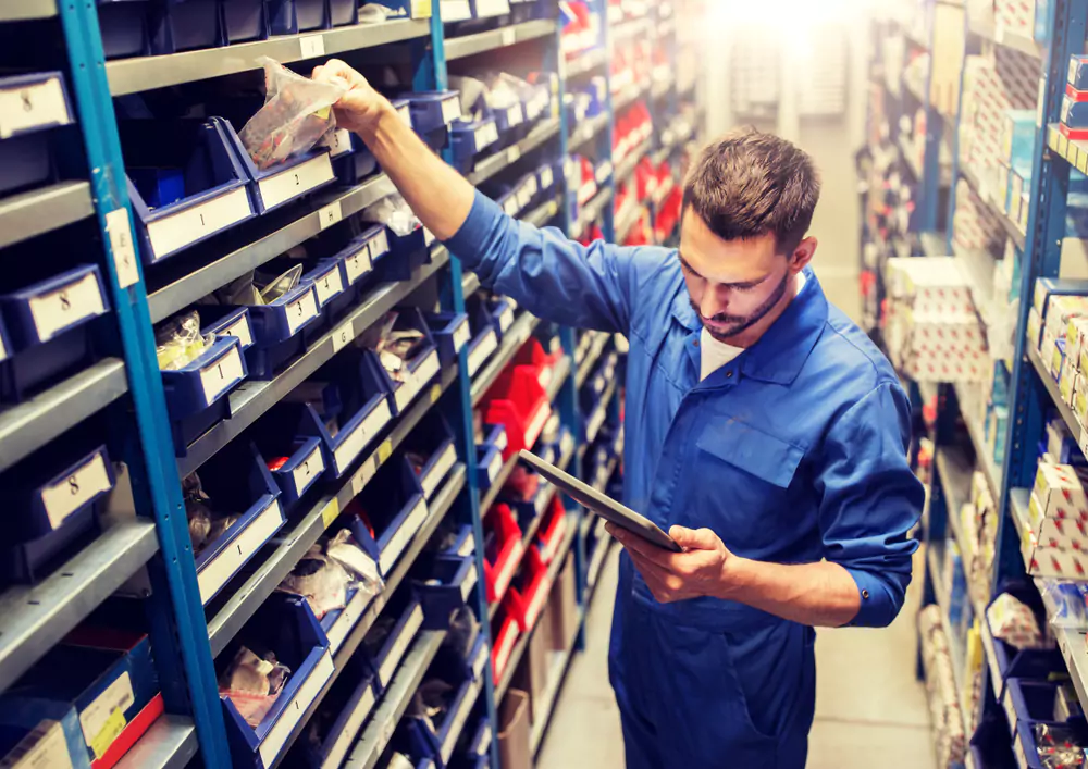 man in warehouse picking an item from a bin on a warehouse shelf