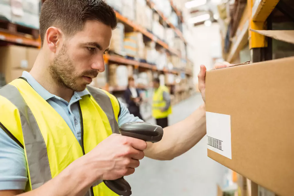 man scanning a barcode on a box in a warehouse