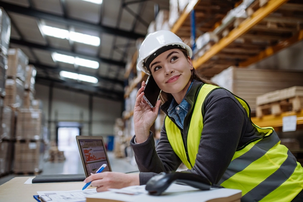 warehouse worker sitting at a desk inside a warehouse on the phone with a customer