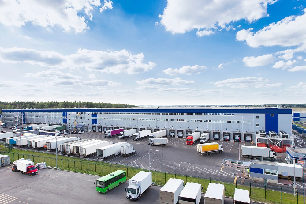 distribution center building with trucks in the parking lot and at the dock loading 