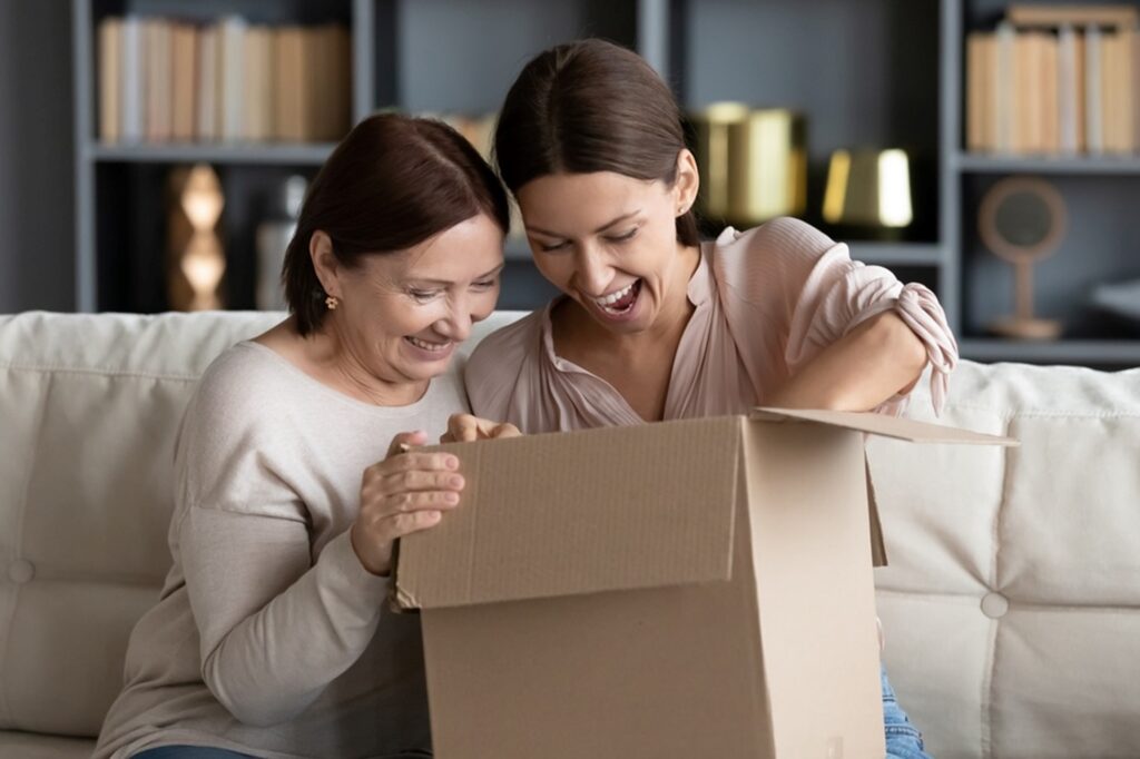 mom and daughter opening a box that came in the mail, both smiling