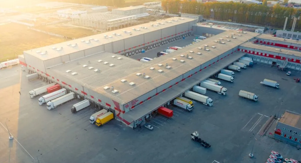 the outside of a distribution center with trucks being unloaded at multiple warehouse docks